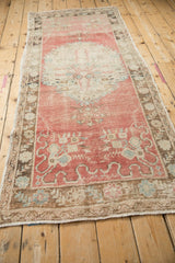 Angled perspective of a vintage Oushak runner showing its distressed texture and faded blush pink field.