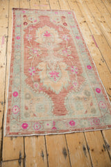 Distressed Oushak runner's oversized palmette, magenta blossoms, and time-softened tones.