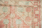 Distressed vintage Oushak rug's muted blush pink and faded turquoise geometric designs.