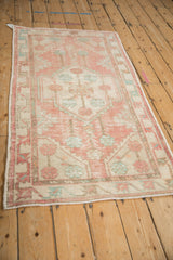 Distressed vintage Oushak rug corner with geometric dusty pink and faded turquoise floral motifs.