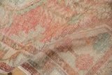 Folded close-up of vintage Oushak rug's distressed pile in faded blush, ivory, and turquoise.