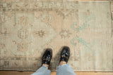 Distressed Oushak runner's textured pile in muted beige, sand, and pale seafoam green.