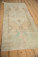Distressed Oushak runner with faded beige and ocean green field, showing simplistic plant motifs and worn texture.