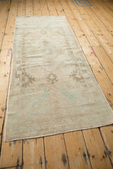 Distressed vintage Oushak runner, muted beige field, faded ocean green and brown patterns.