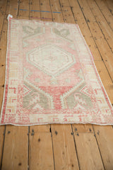 Angled view of a distressed vintage Oushak runner with a faded pink and silver medallion.