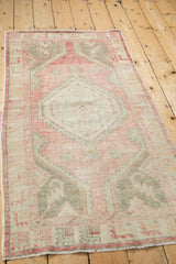 Angled view of a vintage Oushak runner highlighting its distressed texture and geometric medallion.