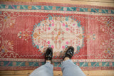 Vintage distressed Oushak rug runner showing heavy abrashes, raspberry field, and ivory medallion with blossoms.