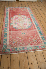 Close-up vintage Oushak runner with raspberry abrashes, turquoise border, and intact selvage.