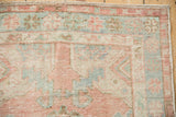 Distressed vintage Oushak rug corner with mostly even wear, dusty rose, and mint green motifs.