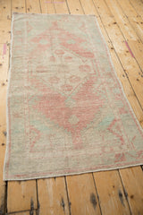 Distressed Oushak rug runner showing worn pile, faded dusty blush and pale green patterns.