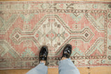 Distressed Oushak runner with dusty rose and seafoam green geometric patterns viewed from above.