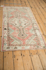 Angled perspective of a distressed Oushak runner with a faded rose and green geometric medallion.
