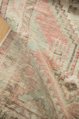 Distressed low-pile texture of a vintage Oushak rug in dusty rose, sea foam, and brown tones.