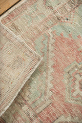 A folded corner showing the hand-knotted foundation and side selvage of a vintage Oushak rug.