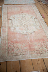 Distressed vintage Oushak runner showcasing muted rose and ivory floral medallion on an abrashed field.