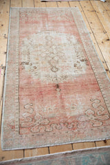 Distressed central floral medallion with faded dusty rose and ivory abrashed pile.