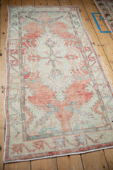 A vintage Oushak runner's distressed texture and geometric design from an angled perspective.