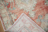 Folded corner of a distressed Oushak rug showing its hand-knotted foundation and low-pile texture.