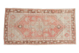 Distressed vintage Oushak runner with a faded red diamond medallion, ivory field, and floral brown border.