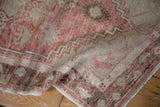 Time-softened texture of a distressed Oushak rug with faded cherry red and warm beige patterns.