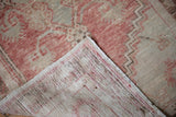 Hand-knotted foundation and low pile of a distressed Oushak rug in faded red and beige.