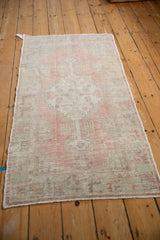 High-angle view of the distressed Oushak runner's faded stepped medallion in rose and silver tones.