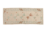 Distressed vintage Oushak runner rug with cream, mint green, and copper floral patterns.