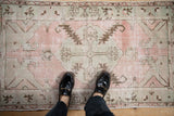 Distressed pink and oxidized silver Oushak rug showing coffee brown floral and serrated leaf motifs.