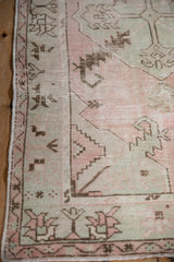 Distressed vintage Oushak rug corner with pink, oxidized silver, and coffee brown floral and serrated leaf patterns.