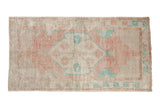 Vintage distressed Oushak runner with a faded shield medallion in dusty rose, turquoise, and ivory.