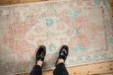 Looking down at the low pile and faded medallion of a vintage distressed Oushak runner.