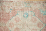 Distressed Oushak rug pile showing visible knot heads in dusty rose, ivory, and pale turquoise.
