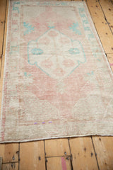 Angled view of a distressed Oushak rug runner showing its worn, low pile and faded colors.