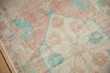 Worn, hand-knotted texture of a vintage Oushak rug in dusty rose, ivory, and pale turquoise.