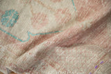 Worn, hand-knotted texture of a vintage Oushak rug in dusty rose, beige, and turquoise.