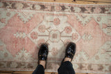 Vintage distressed Oushak rug runner showing muted dusty rose and ivory floral pattern, soft texture.