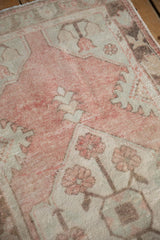 Distressed vintage Oushak runner pile with muted dusty rose, ivory, and soft green motifs.