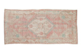 Vintage distressed Oushak runner with a central medallion in faded raspberry red, ivory, and pale turquoise.