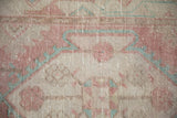 Mostly even wear to the knot heads of a distressed Oushak rug in faded raspberry and turquoise.