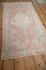 Angled view of a vintage Oushak runner with time-softened raspberry, ivory, and turquoise colors.