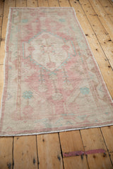 Angled view showcasing the distressed low pile and faded raspberry red of a vintage Oushak runner.