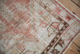Angled view of the distressed Oushak rug's corner, with its low pile and geometric border.