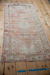 Angled view down the length of a distressed Oushak runner in dusty rose and ivory.
