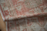Folded corner of a distressed Oushak runner showing its low pile and intact side cord.
