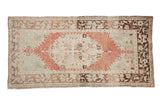 Vintage distressed Oushak runner with a raspberry red medallion on a sea foam green and brown field.