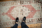 Abrashed low pile of a distressed Oushak runner in dusty raspberry, sea foam, and brown tones.