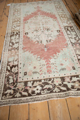 Angled view of a vintage Oushak runner with its raspberry medallion and brown floral border.