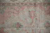 Close-up of the distressed, hand-knotted pile showing blush, sea foam, and coffee brown tones.