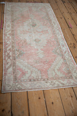 Angled view of a vintage distressed Oushak runner, showing its soft blush, ivory, and sea foam hues.