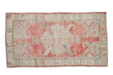 Distressed vintage Oushak rug runner with a large-scale medallion in raspberry red and dusty celadon green.
